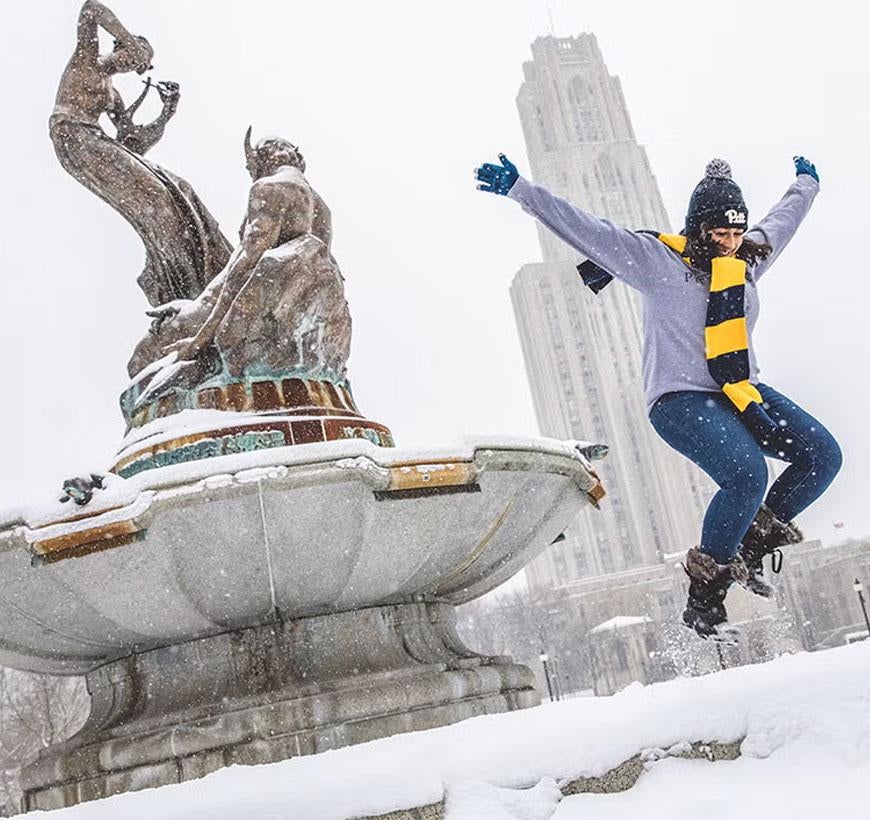Student jumping off fountain in snow